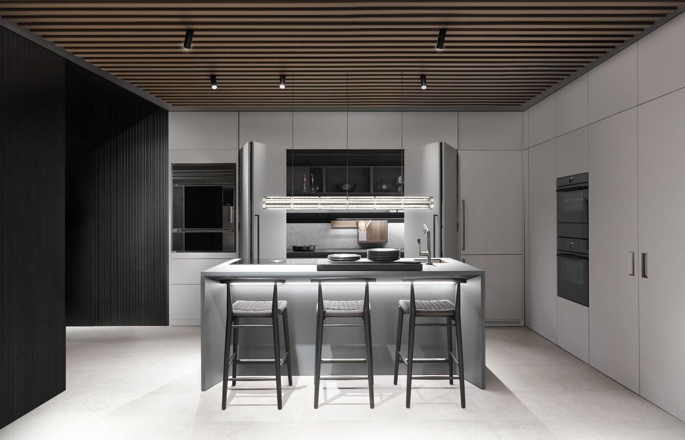 Grey kitchen island with table settings and bar stools, flanked by tall storage columns and integrated appliances, seen from a slightly wider angle