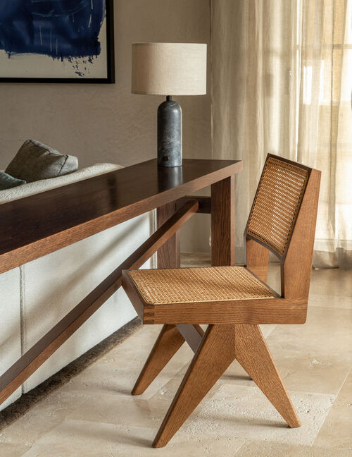detail of wood desk and woven chair near window light
