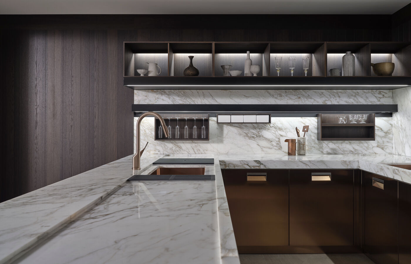 A third zone features the refined modernism of the Italia in bronze PVD with a Calacatta marble worktop and framed by a Modus System in NTF fumé oak. A marble back panel is featured, adorned with Mensolinea shelf.  This layout is imagined with the harmony of family life in mind and the pleasure of daily connections.