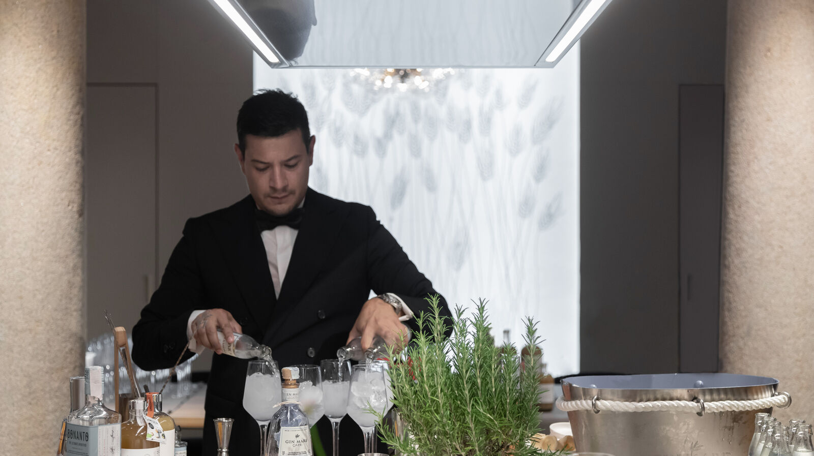 Bartender pouring spirits into glasses with ice on Arclinea kitchen counter during MDW22 event