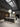  A showroom aisle with two dark wood kitchen islands under bubble-cluster pendant lights and a skylight