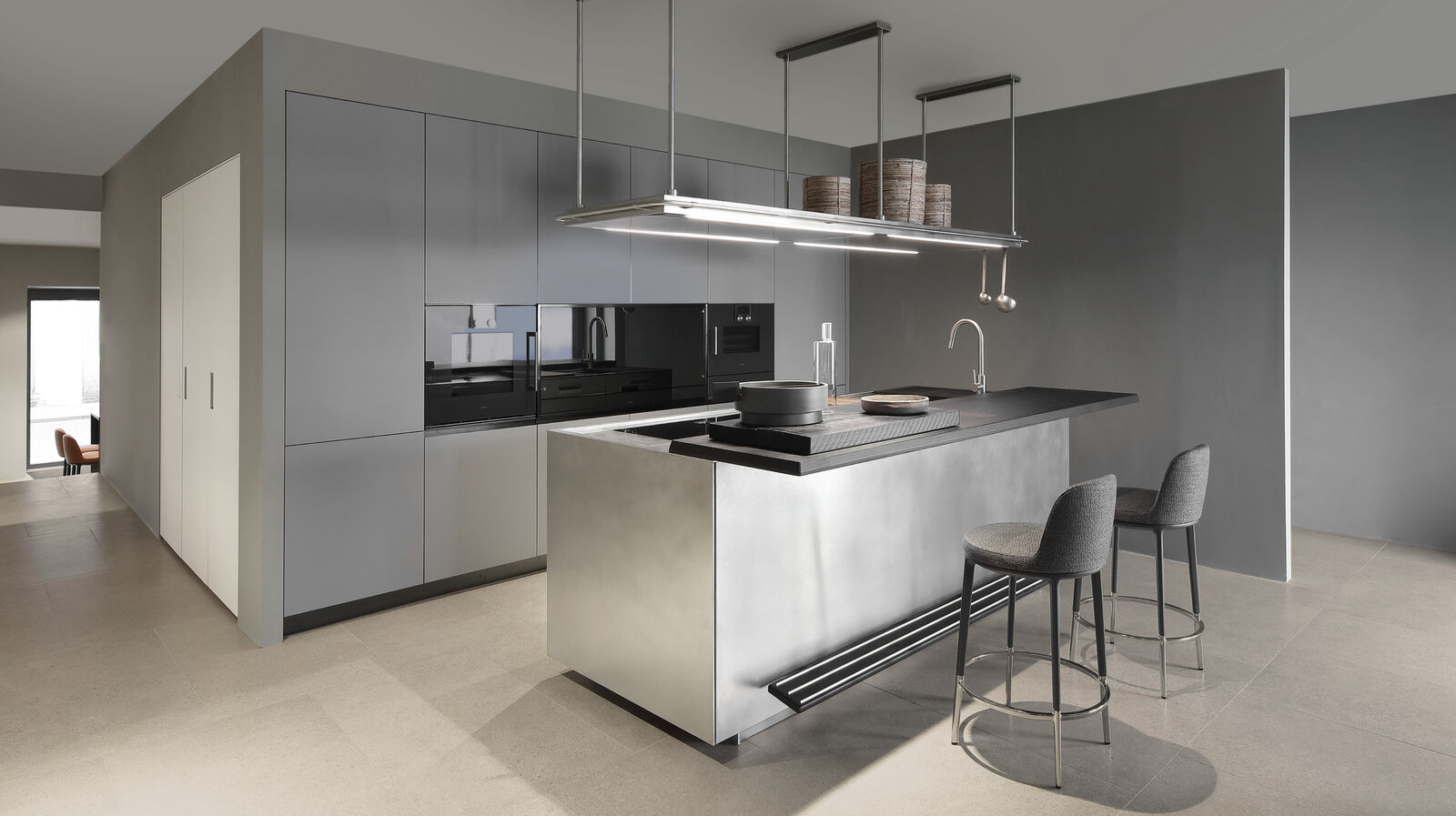 Grey kitchen with steel island, black worktop and bar stools