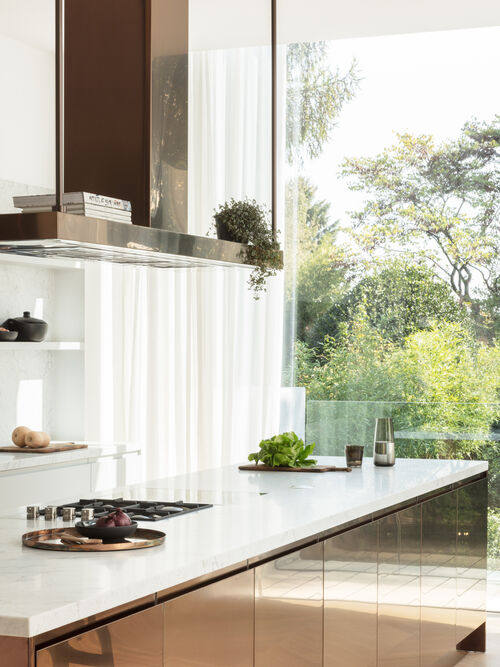 Arclinea kitchen countertop with hood and view of garden through glass wall