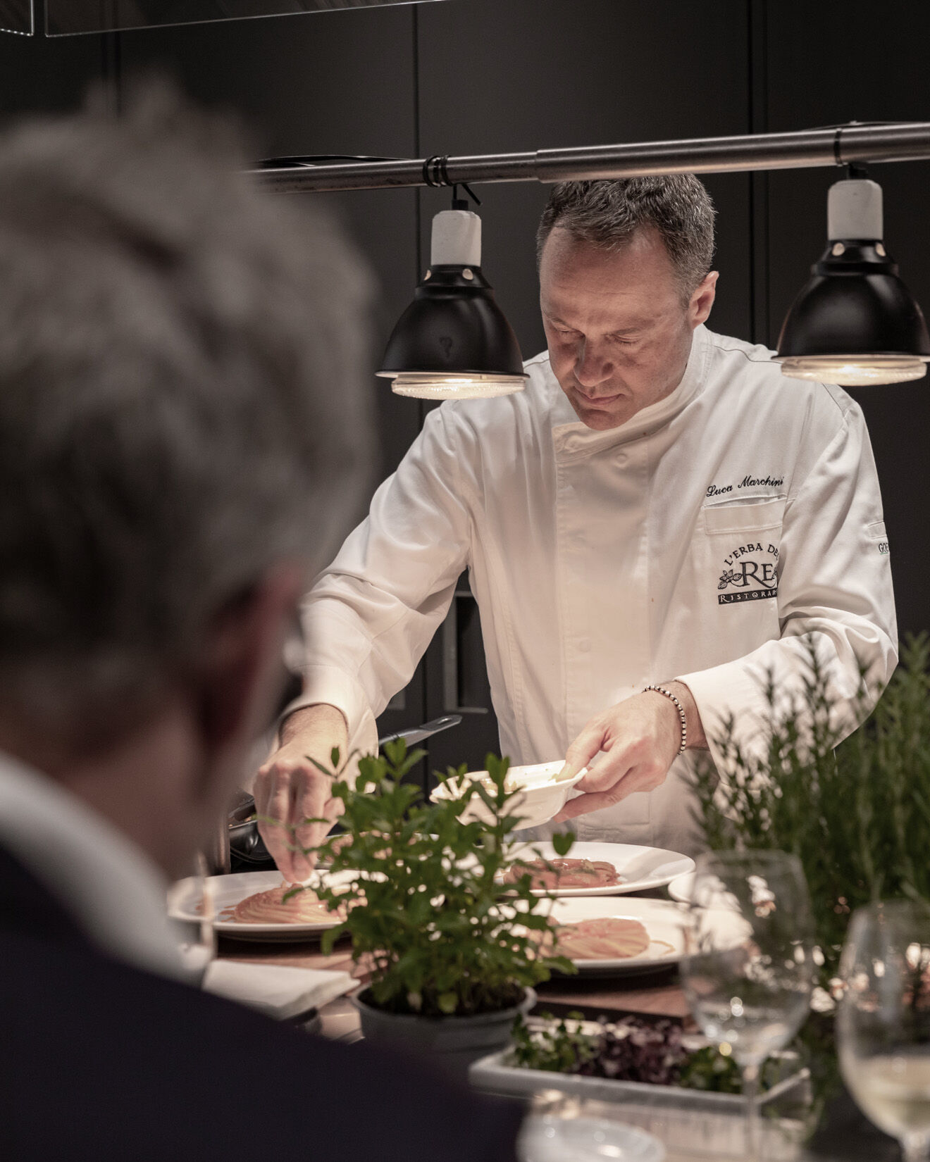 Chef plating herb garnish on dishes at Arclinea kitchen island during MDW22 dinner event