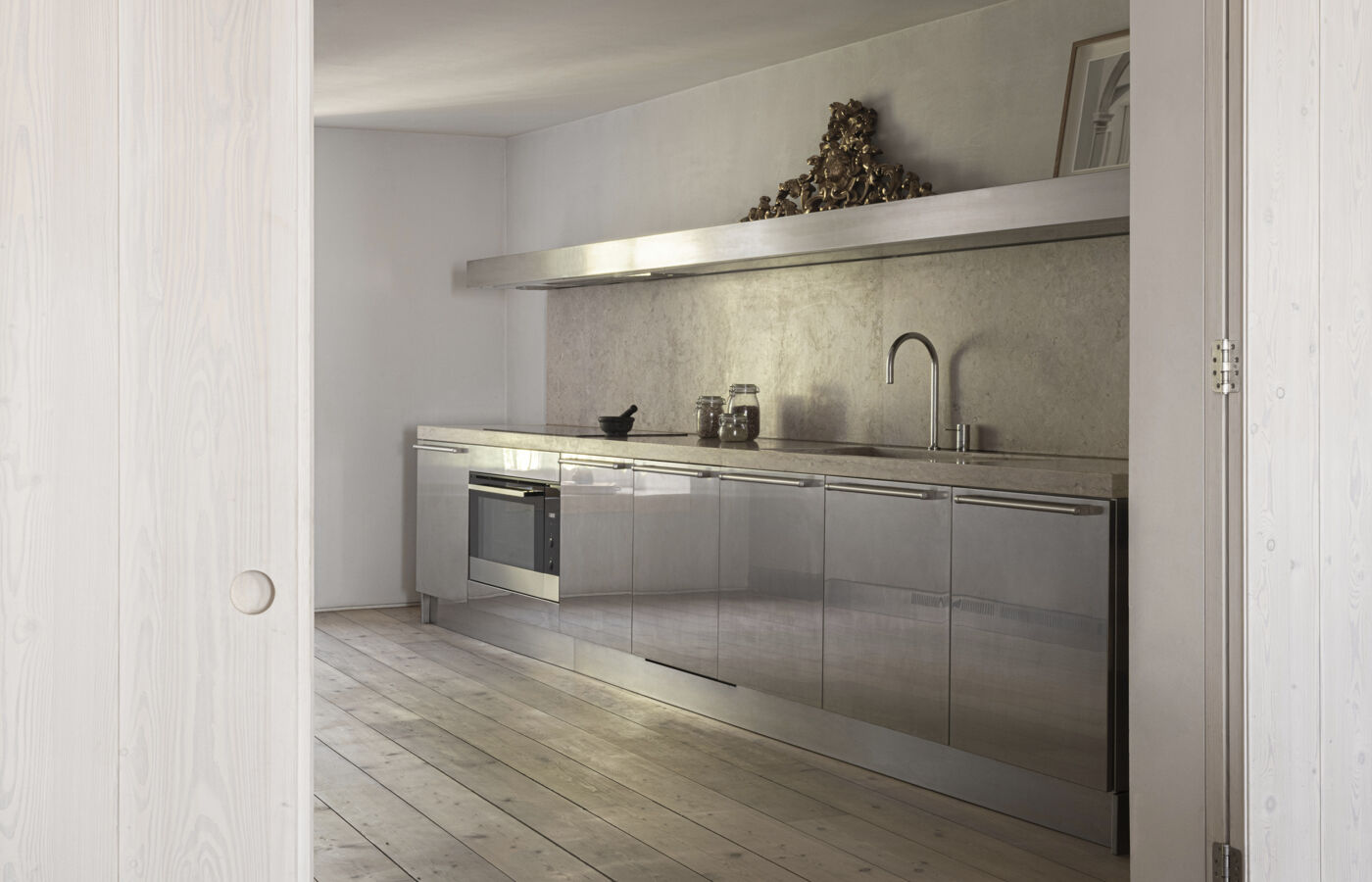 Arclinea Artusi kitchen with stainless steel cabinetry and natural stone backsplash