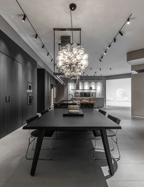 Arclinea showroom with black dining table, sphere chandelier and dark cabinetry