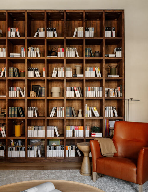 Warm reading nook with wood shelving in a residence showcasing an Arclinea kitchen