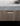 Close-up detail of a marble countertop edge and a wood cabinet drawer with a slim black handle, with an open magazine resting on top