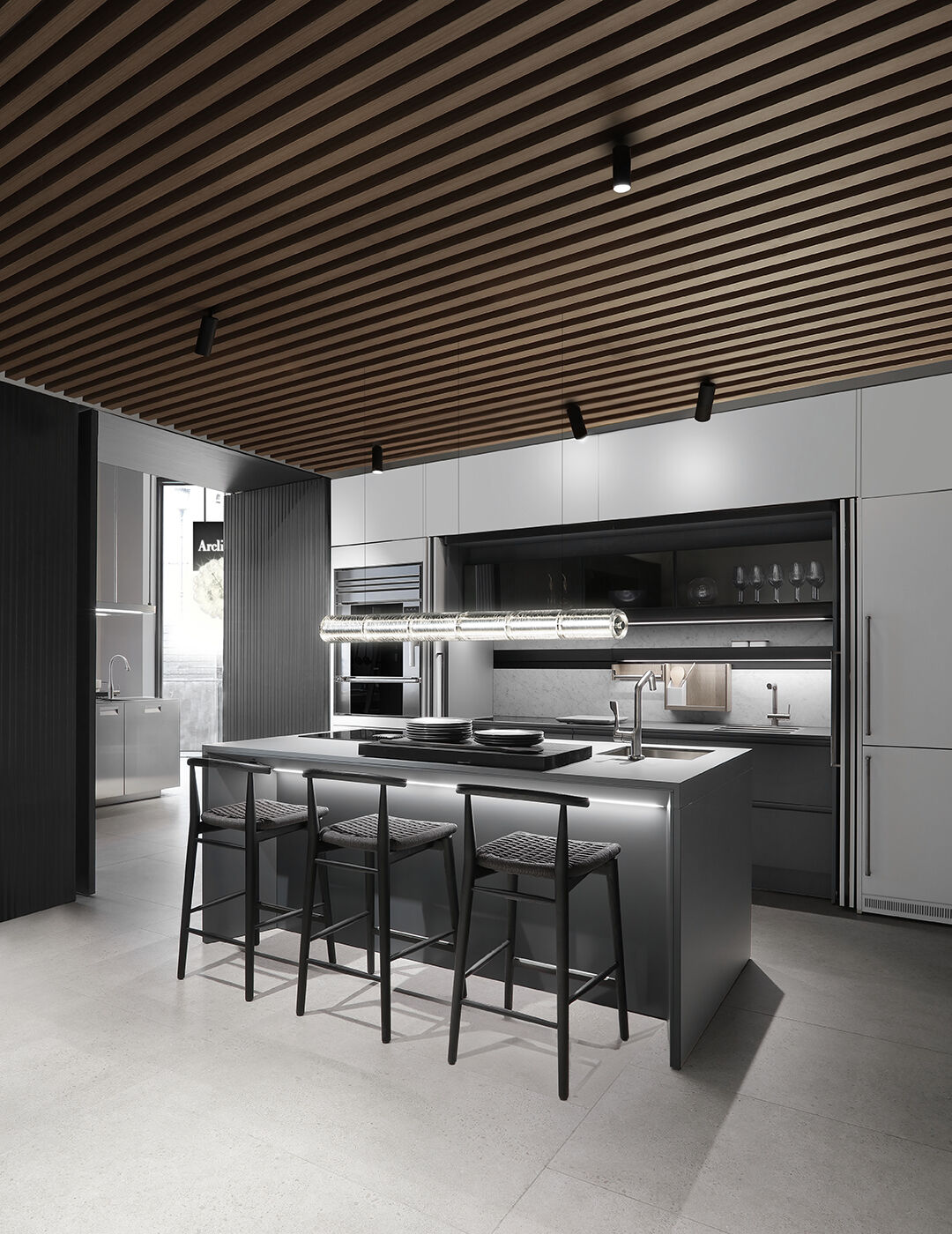 Frontal view of a grey kitchen island with woven-seat bar stools, set beneath a ribbed wood ceiling and backed by full-height storage units