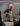 A smiling bald chef in an apron stirs a steaming pot on an induction cooktop as seated guests look on