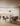 Arclinea dining area with round travertine table and pedestal base, upholstered chairs and panoramic windows with sheer curtains