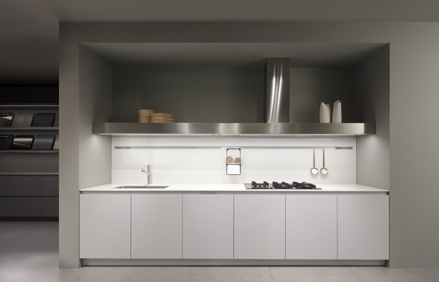 Compact white kitchen niche with a stainless steel hood, marble backsplash and built in gas hob