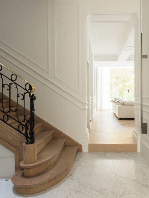 Wooden staircase with wrought iron railing leading to hallway with marble floor