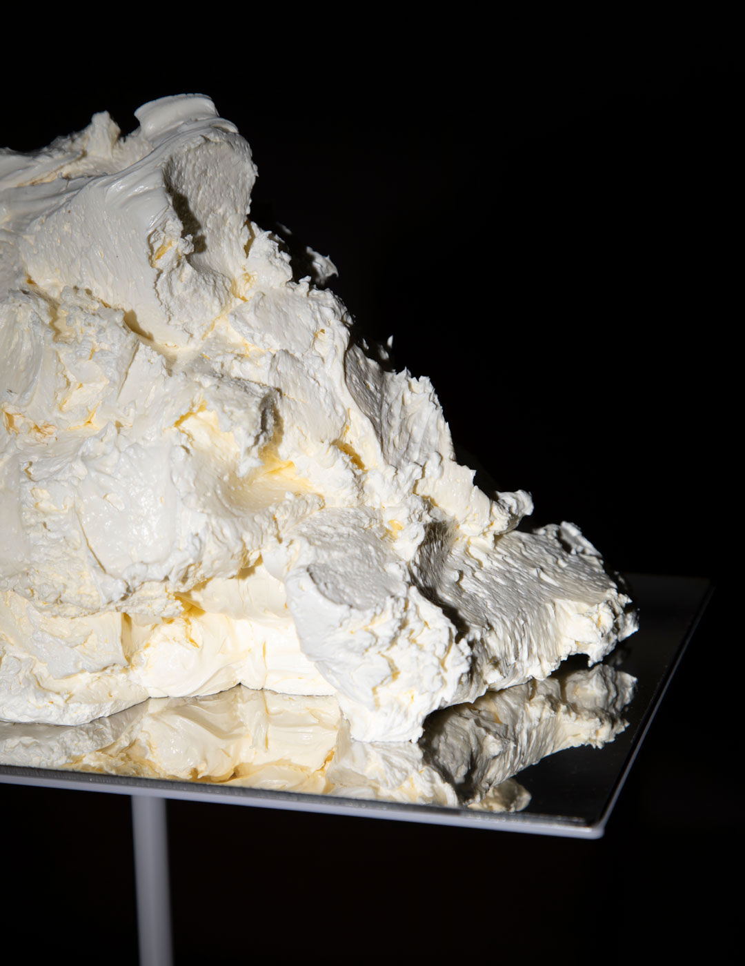 A server in a white shirt holds a metal tray lined with a row of amber gelatine cubes dusted with spice