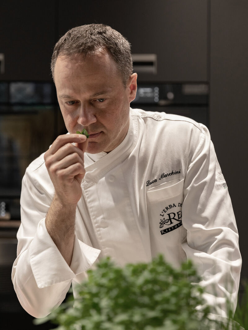 Chef smelling fresh herbs before plating at Arclinea kitchen during MDW22 event